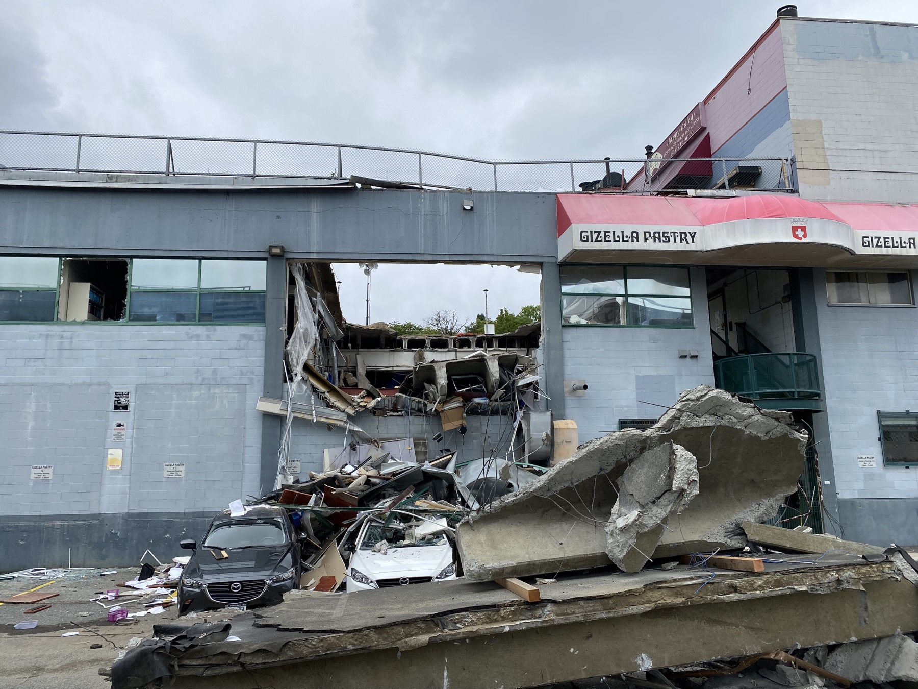 Close view of collapsed rooftop parkade, debris, and damaged building elevation