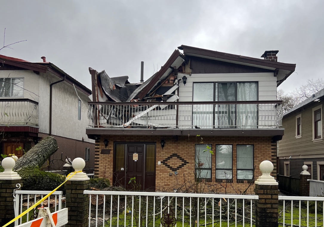 Residential roof and upper wall damage after a tree impact event